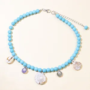 Detailed close-up of blue bead necklace with seashell charms and silver lobster clasp