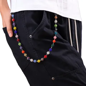 Dettaglio della catena da vita con strass colorati su pantaloni cargo neri da donna