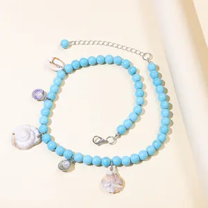 Detail of bohemian turquoise beaded necklace with various seashell pendants and lobster clasp