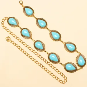 Detail of vintage gold chain belt with turquoise teardrop stones and floral pendant