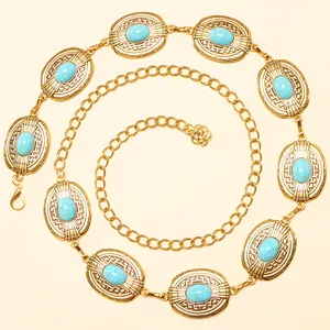 Détail de la chaîne de taille dorée avec pierres turquoise et pendentif floral