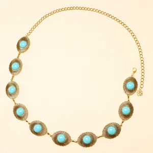 Détail d'une chaîne de taille dorée bohème avec turquoises ovales et pendentif fleur