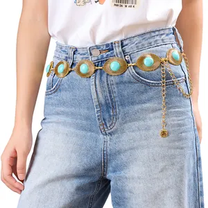 Chaîne de taille bohème en métal doré avec ovales turquoise sur un jean bleu clair
