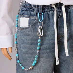 Broekketting met turquoise schedels en metalen kralen op vintage denim spijkerbroek