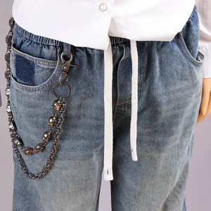Close-up of double-layered punk skull pants chain hanging on blue denim jeans