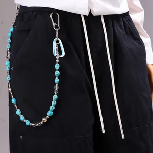 Detail van broekketting met turquoise schedel, zilveren kralen en karabijnhaakjes