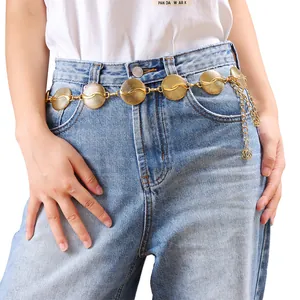 Détail de la chaîne de taille en métal doré avec turquoise sur un mannequin en jean bleu