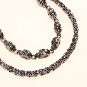 Detail of heavy punk silver chain featuring 3D skull charms and Byzantine weaving