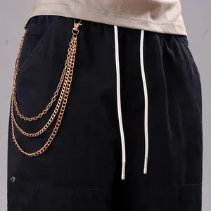Detail of three-layer gold metal chains on black cargo pants with beige drawstring