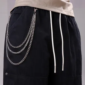 Detail of hip hop style multi-layer silver chains on black trousers with white drawstrings