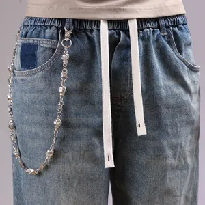 Detail of blue denim jeans with skull metal pants chain and thorns link decoration