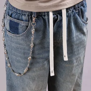Close-up of silver skull trousers chain on vintage washed blue denim jeans detail