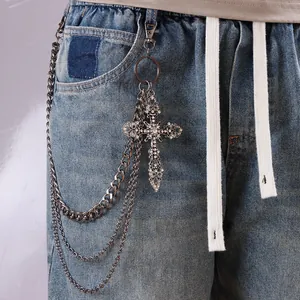 Cadena de pantalones multicapa plateada con cruz de diamantes sobre jeans azul