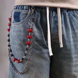 Detalle de cadena de pantalón plateada multicapa con corazones rojos y cuentas negras