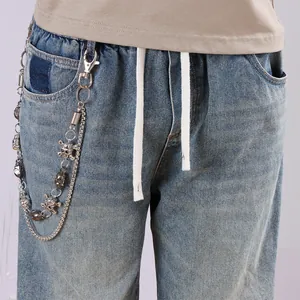 Detail of double-layer punk metal waist chain with skull charms on blue denim jeans