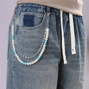 Détail d'une chaîne de taille double couche avec perles et turquoise sur un jean en denim