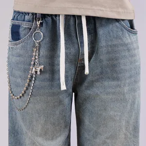 Detail of light blue washed denim jeans with silver chain and a small horse pendant