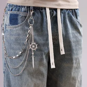 Detail of multi-layer silver waist chain with rudder and sword pendants on denim jeans