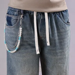 Détail d'un jean vintage avec chaînes argentées multicouches et perles turquoise élégantes