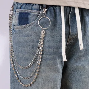 Detail of layered silver metal pant chains with beads and lobster clasps on denim jeans