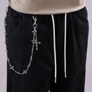 Détail d'une chaîne croisée vintage argentée avec pendentif tête de mort sur pantalon