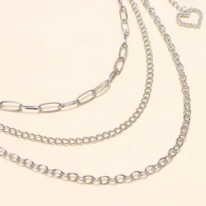 Vue macro d'une chaîne de pantalon argentée multicouche avec pendentif cœur brillant