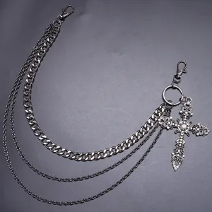 Detalle de cadena de pantalón multicapa gris oscuro con colgante de cruz de diamantes