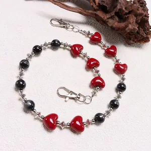 Detalle de cadena gótica con cuentas de corazón rojo y ojo de gato negro en metal