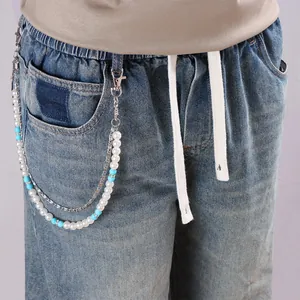 Détail d'une chaîne de taille multicouche en turquoise et perles sur un jean