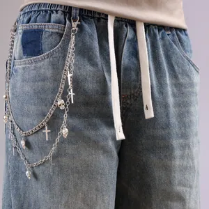 Detail of silver multi-layer metal pants chain with skull and cross charms on denim jeans
