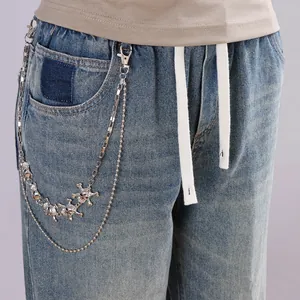 Détail d'une chaîne de pantalon double en argent avec breloques crânes punk et fermoirs mousquetons