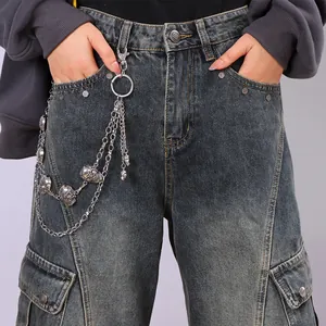 Dettaglio della catena a teschio multistrato su pantaloni cargo in denim lavato
