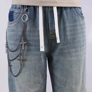 Detail of light blue washed jeans featuring drawstring waist and multilayer cross pant chain