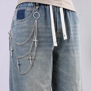 Detailed view of triple-layered metal pants chain with cross pendants on blue denim jeans