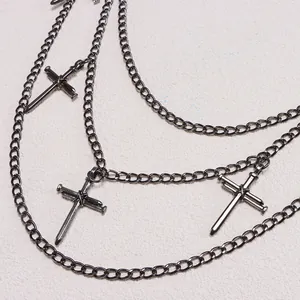 Detail of layered metal pant chains with cross nail pendants in industrial punk style