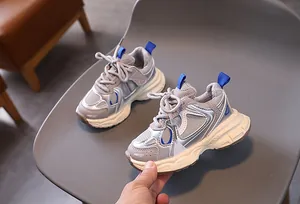 Detailed view of children's grey sneakers with blue accents and thick white soft sole