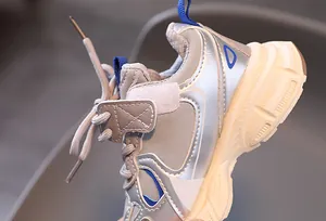 Close-up of children's silver sneakers showing breathable mesh and stitching detail