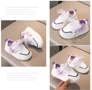 Dettaglio di scarpe bianche bambina con farfalla glitter viola e lacci in tulle