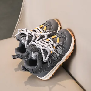 Détail de baskets enfant gris et orange montrant coutures en cuir synthétique et semelle texture