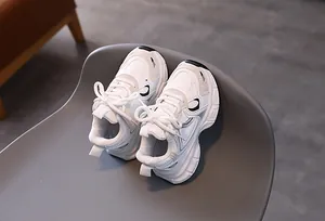 Close-up of white breathable mesh kids sneakers on a modern chair indoors