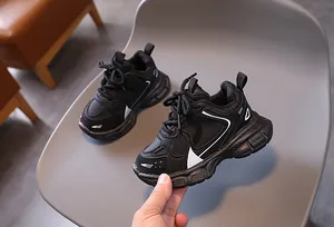 Close-up of black kids sports sneakers showing mesh texture and non-slip thick sole