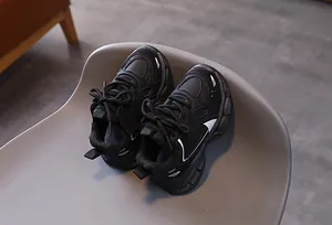 Detail view of children's thick-soled sneakers with black synthetic leather and mesh design
