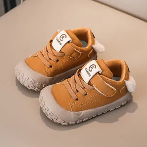 Macro shot of ginger yellow toddler sneakers with rubber toe and pom-pom detail