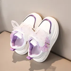 Dettaglio di sneakers in pelle bianca da bambina con ricamo a farfalla viola e lacci in organza