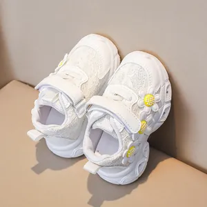 Close-up of girls white sneakers with lace mesh and decorative yellow daisy flowers