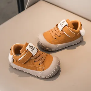Detail of baby walking sneaker in mustard yellow with velcro strap and plush pompom heel