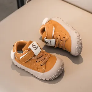 Close-up of ginger yellow leather baby sneakers with Velcro strap and non-slip rubber sole