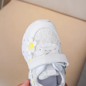 Detail of girls' white lace sneakers featuring daisy accents and velcro straps