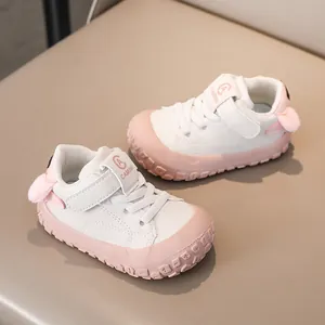 Detail view of baby sneakers featuring pink plush pom-poms and leather hook-and-loop straps