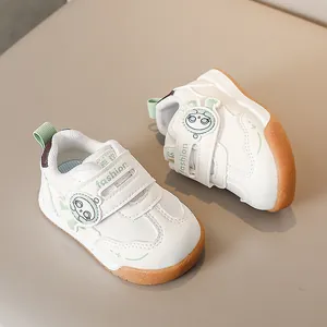 Dettaglio di scarpe per neonati con chiusura a strappo, accenti verdi e patch cartoon